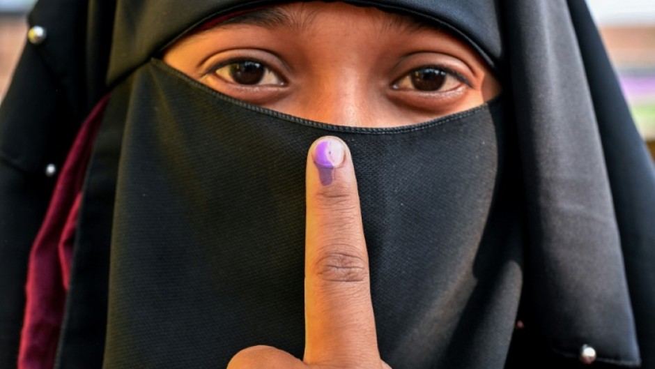 A woman shows her inked finger after casting her ballot at a polling station during the second phase of voting in India's general election