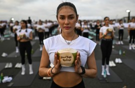 A yoga enthusiast holds a coconut during the sunrise yoga event