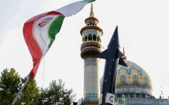 Iranians in central Tehran lift up a flag and the mock-up of a missile during a celebration following Iran's unprecedented attack by missiles and drones on Israel