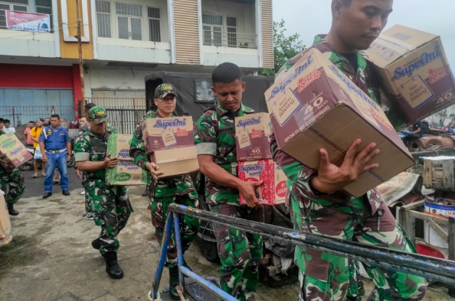 Indonesian military personnel load food items onto a ship as they head to the island near Mount Ruang volcano after it erupted