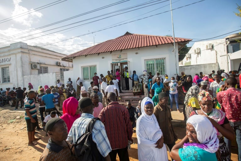 More than a hundred people wait on the outskirts of the port of Pemba