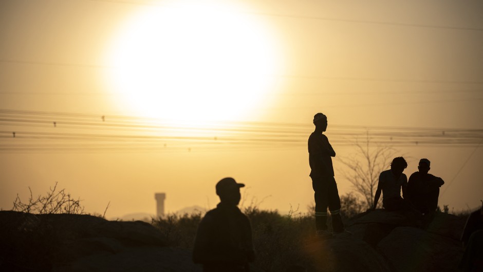 File: People are silhouetted as they gather at Wonderkop in Marikana, Rustenburg where striking miners were killed during the Marikana massacre. GULSHAN KHAN / AFP