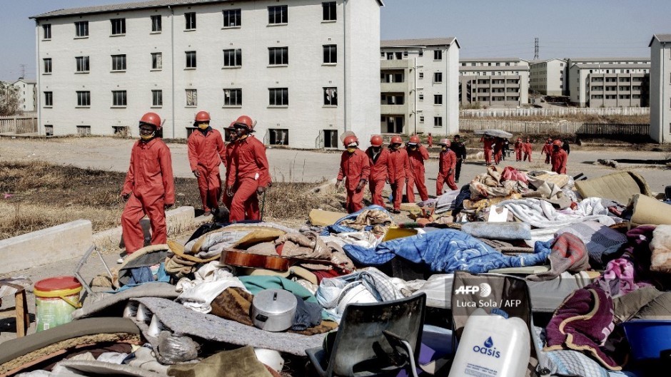 Members of the Red Ants stand next to personal belongings of people they removed from the apartments during a joint eviction operation between the Red Ants and the South African Police Service (SAPS) of people that illegally occupied apartment buildings in Roodepoort, near Johannesburg.