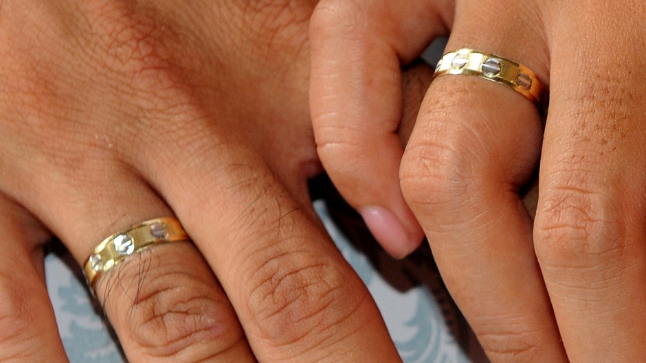 File: A couple holding hands during a wedding.