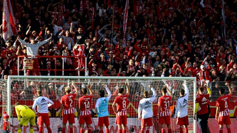 Union Berlin players celebrate with their fans after beating Wolfsburg to stay top of the Bundesliga 