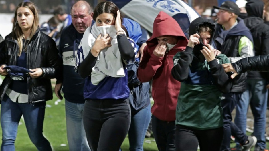 Fans of Gimnasia y Esgrima escape unrest nad tear gast by reaching the soccer pitch after violence and police operations near an Argentina soccer match between Gimnasia and Boca Juniors in La Plata