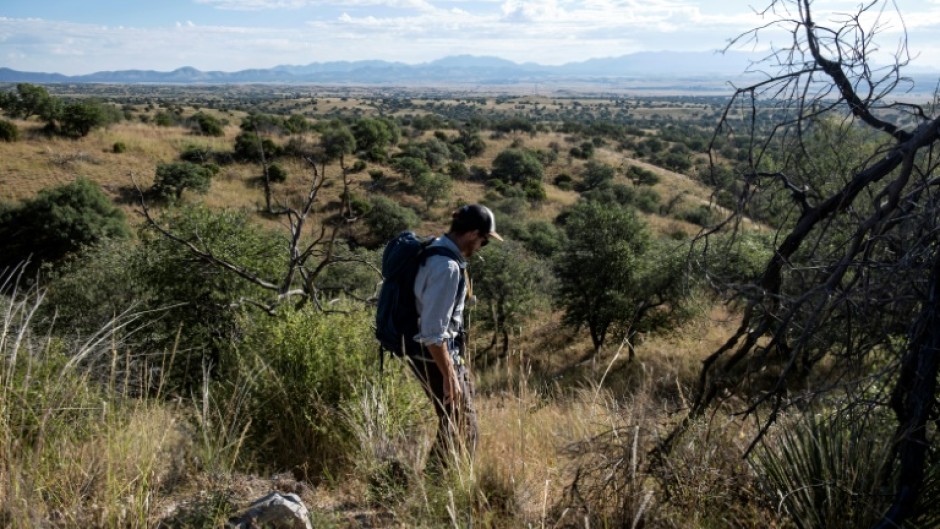 Conservationist Eamon Harrity walks near the US-Mexico border to collect images from a trap camera