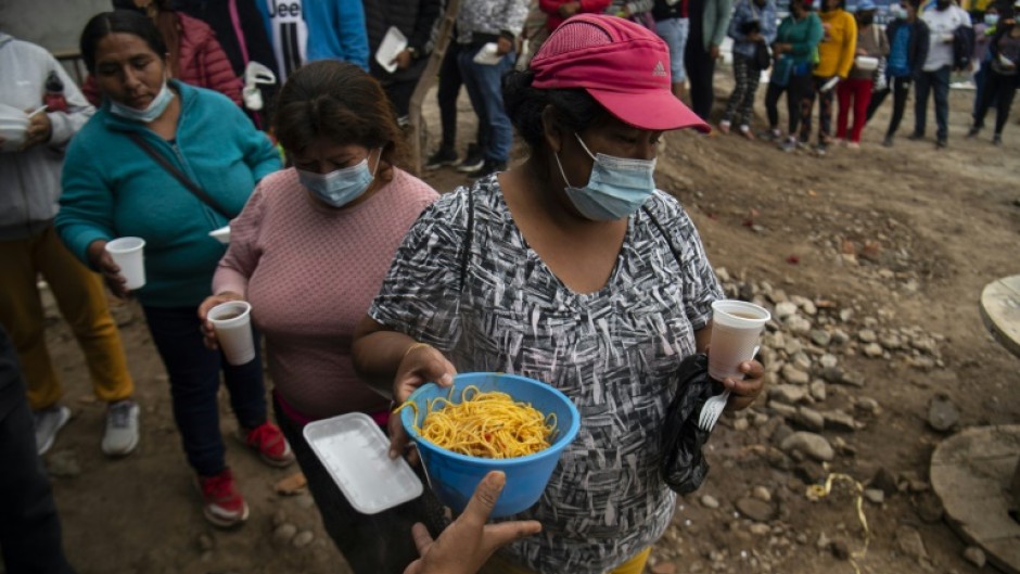 People queue for food at a soup kitchen in Peru