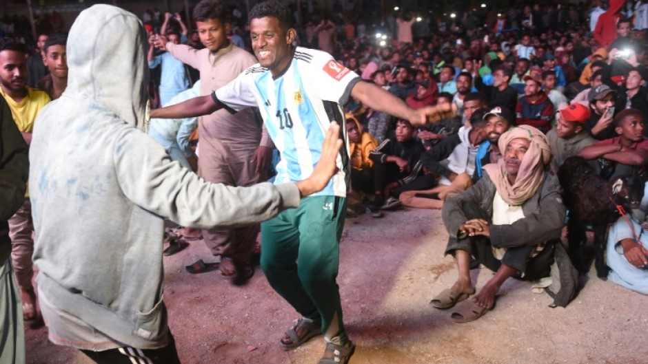 Pakistani football fans dance as they watch the live broadcast of the World Cup semi-final between Argentina and Croatia in the Lyari neighbourhood of Karachi