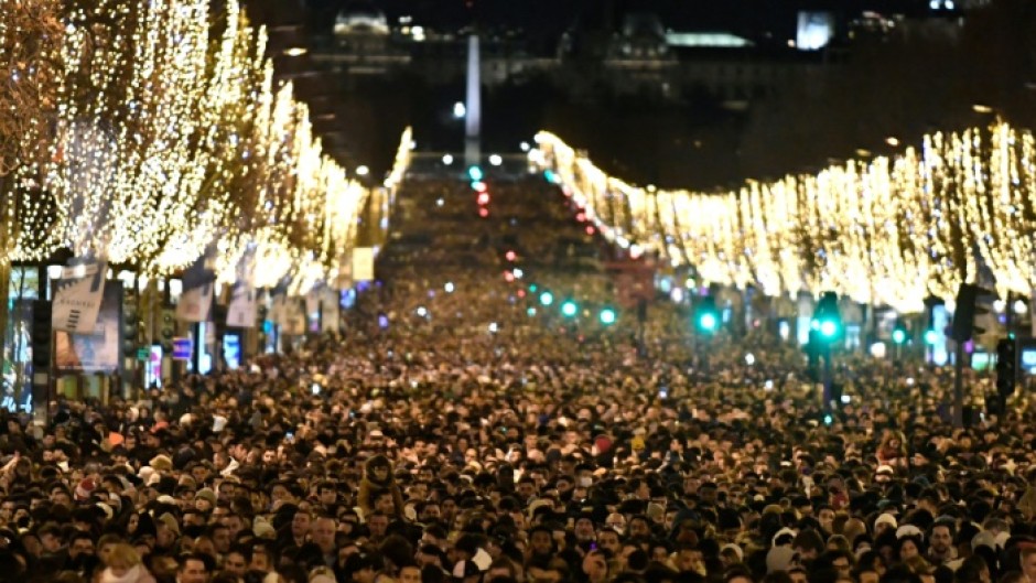 People gather on the Champs-Elysees as they wait for the New Year's Eve fireworks in Paris on December 31, 2022