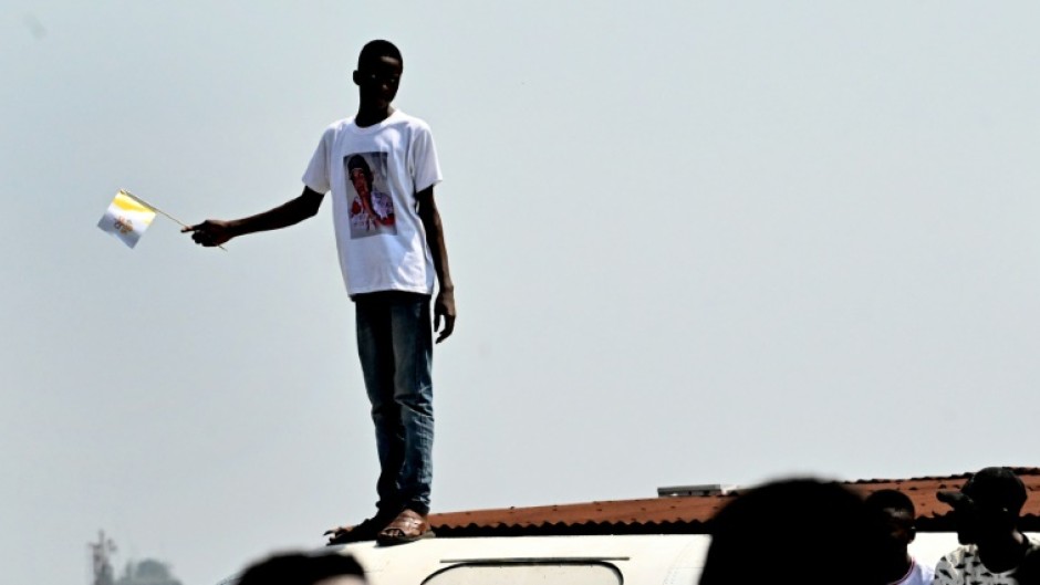 Greeting: A young man waves a flag to welcome the pope