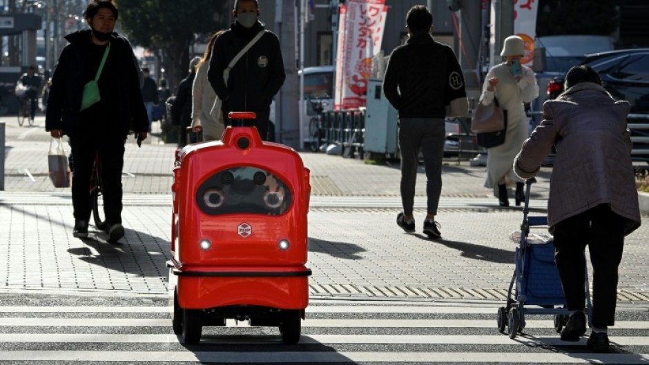 A four-wheeled robot dodges pedestrians on a street outside Tokyo, part of an experiment businesses hope will tackle labour shortages and rural isolation