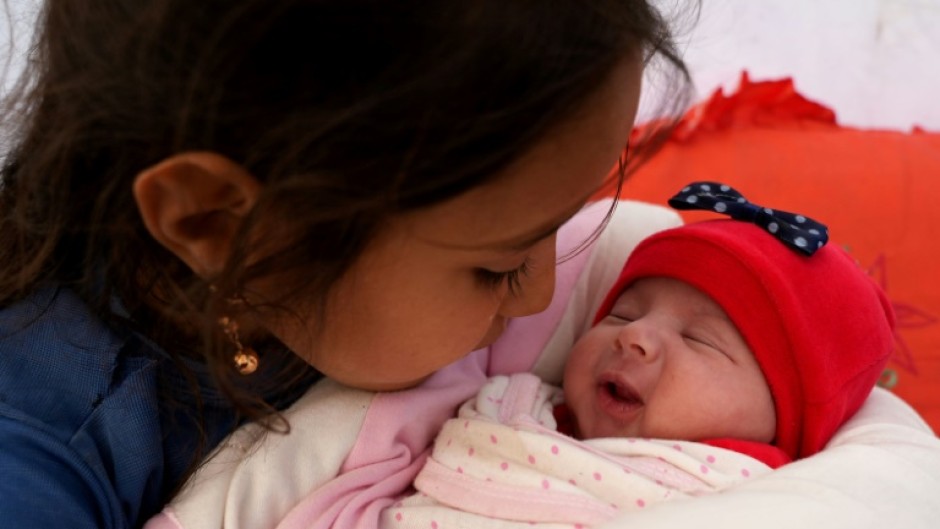 Khalil al-Suwadi's daughters gathered around the baby, embracing and kissing her