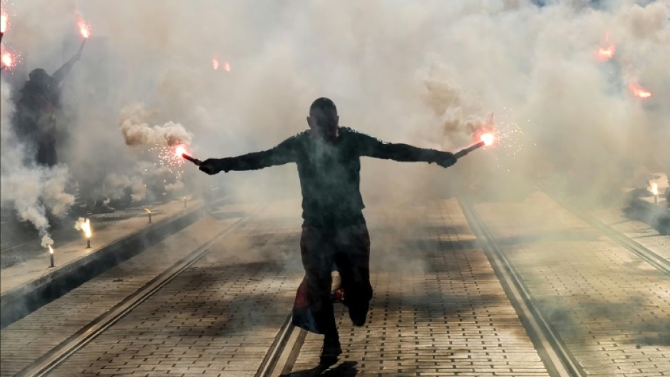 A protester holds burning flares during a demonstration in Nice