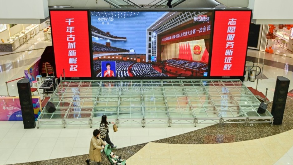 Live coverage of the opening session of the National People's Congress (NPC) is shown at a shopping mall in Qingzhou, China