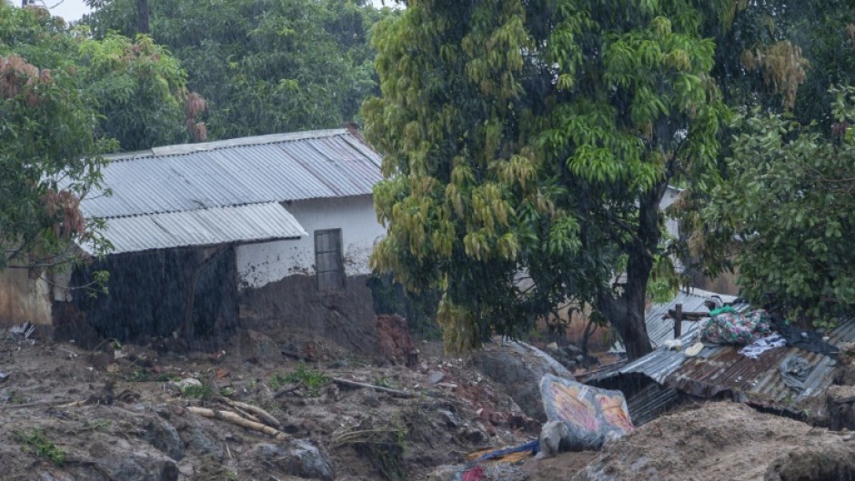 People walk across a makeshift bridge over flood water in Blantyre on Tuesday