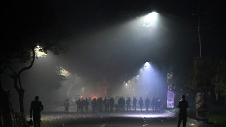 Police stand guard along a street near the residence of former Pakistan prime minister Imran Khan after clashes with his supporters