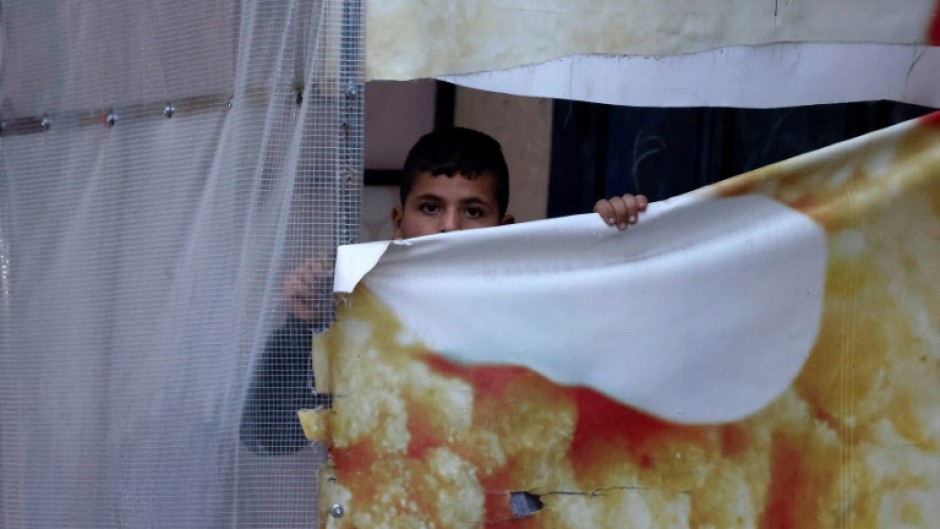 A Palestinian boy peeps at Israeli soldiers patrolling Huwara