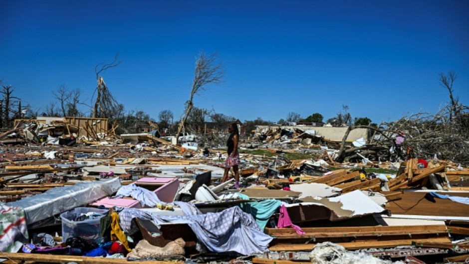 A woman in Rolling Fork, Mississippi walks amid the remains of homes destroyed by a massive tornado that ravaged parts of the southern US state, killing at least 25 people and leaving dozens of others injured