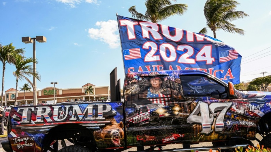 Supporters of former US president Donald Trump wait to greet him upon his arrival from New York near Palm Beach International Airport in Palm Beach, Florida 