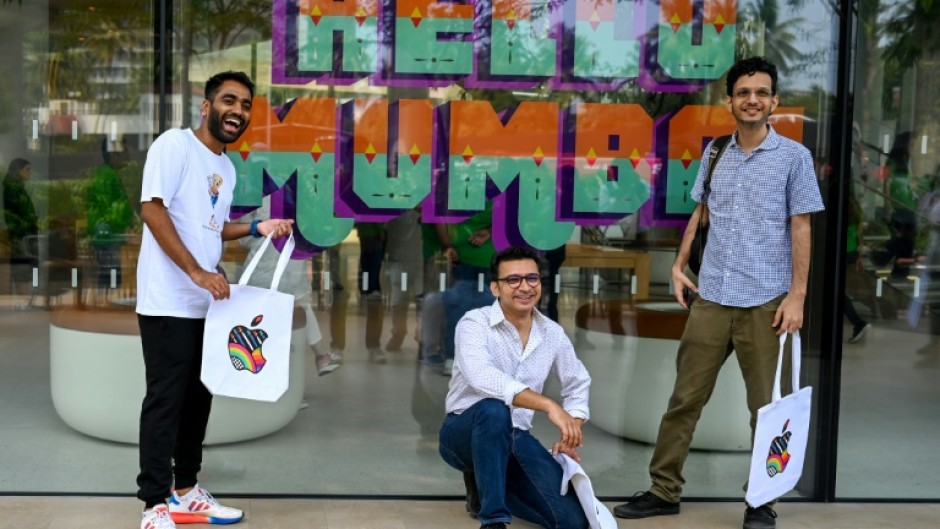 Apple fans pose outside the company's new Mumbai store during a media preview