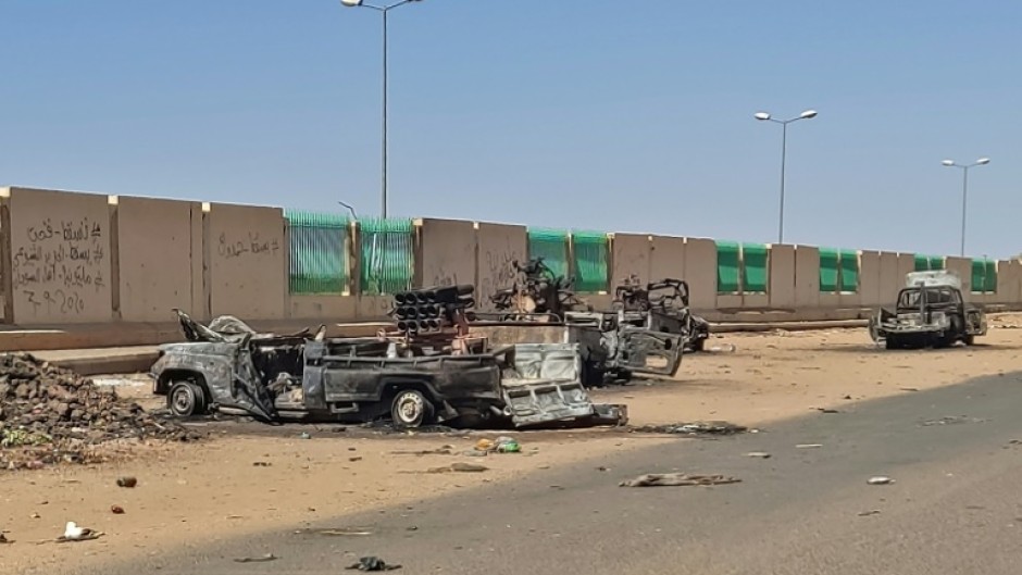 A column of smoke rises behind buildings near the airport area in Khartoum on April 19