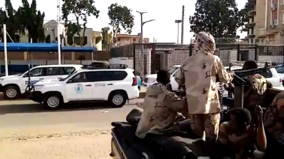 A convoy evacuating foreign citizens leaves Khartoum towards Port Sudan watched by soldiers