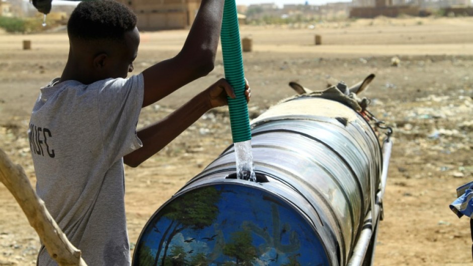 A man fills water into a barrel mounted on donkey-pulled carts in southern Khartoum on April 22, 2023, amid water shortages caused by the ongoing battles between the forces of two rival Sudanese generals