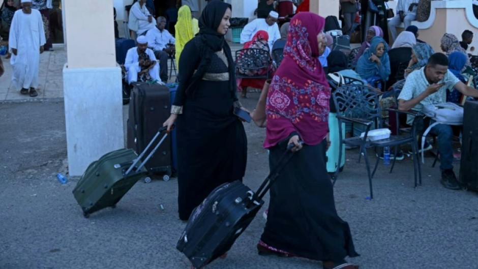 People wait with their luggage at Port Sudan ahead of their evacuation by sea