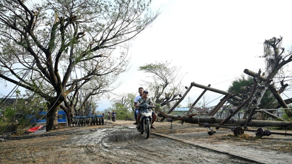 Two men drive past fallen utility poles in Kyauktaw in Myanmar's Rakhine state, hit by Cyclone Mocha