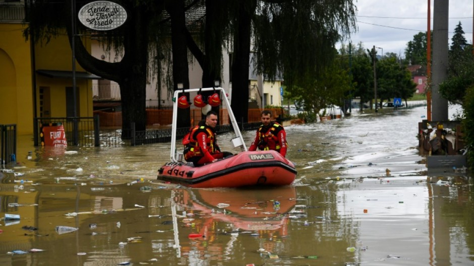 Volunteer firefighters ride their dinghy across a street flooded by the river Savio in the Ponte Vecchio district of Cesena, central eastern Italy, on May 17, 2023