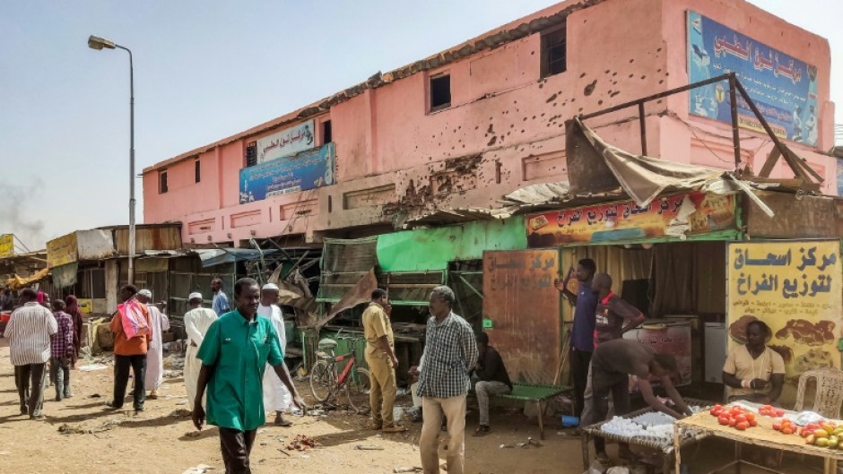 People walk past a medical centre riddled with bullet holes in the Sudanese capital's Souk Sitta