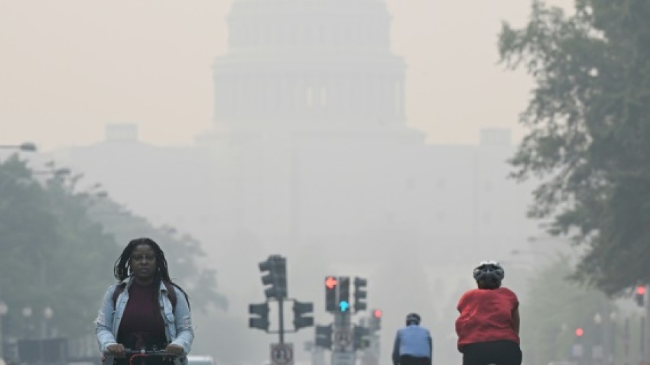 People commute under a blanket of haze partially obscuring the US Capitol in Washington