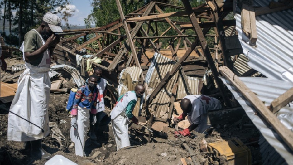 Local Red Cross volunteers attempt to extract a corpse from the rubble of a house destroyed by a landslide