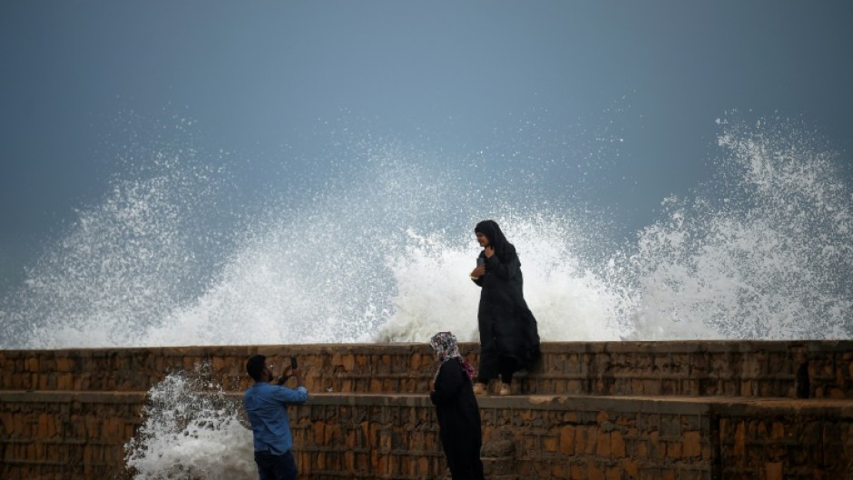 People take photos by a waterfront in Karachi as Cyclone Biparjoy approaches on Wednesday