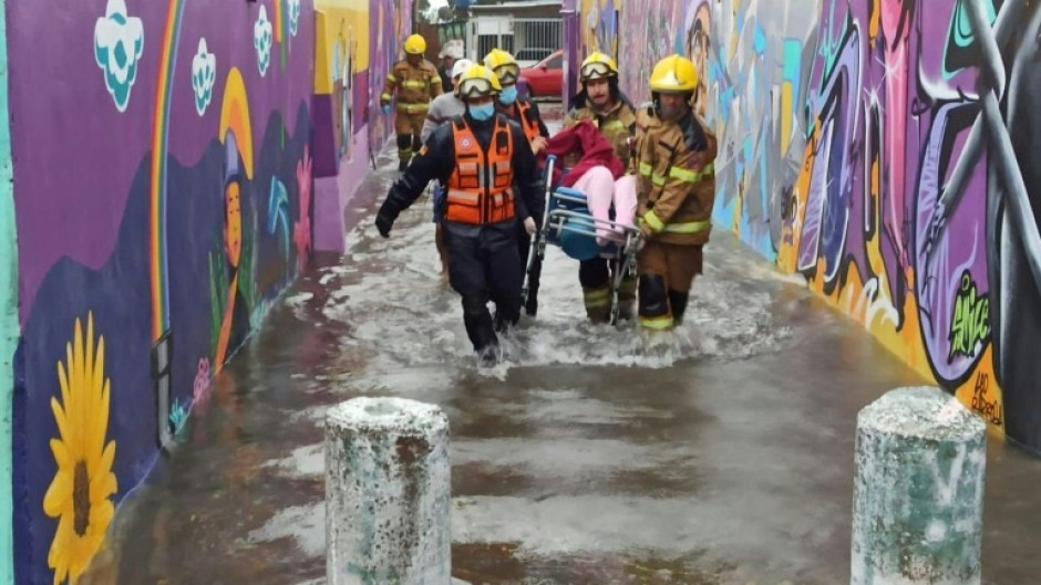 A handout picture released by the Rio Grande do Sul State Government shows firemen carrying a person in a flooded street in Porto Alegre, Rio Grande do Sul State, Brazil