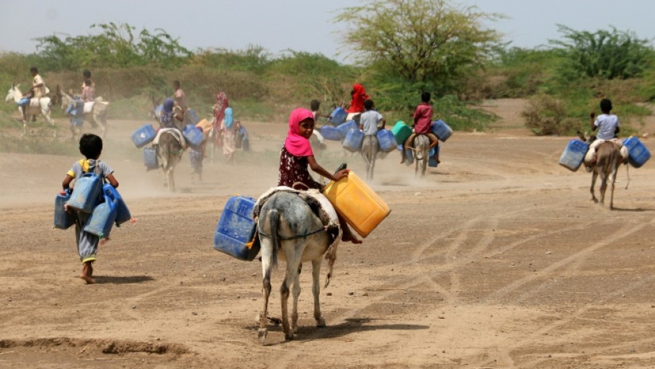 Children ride donkeys to fetch water in jerrycans at a makeshift camp for people who fled fighting between Huthi rebels and the Saudi-backed government forces, in the village of Hays in Yemen's western province of Hodeida, on July 22, 2023