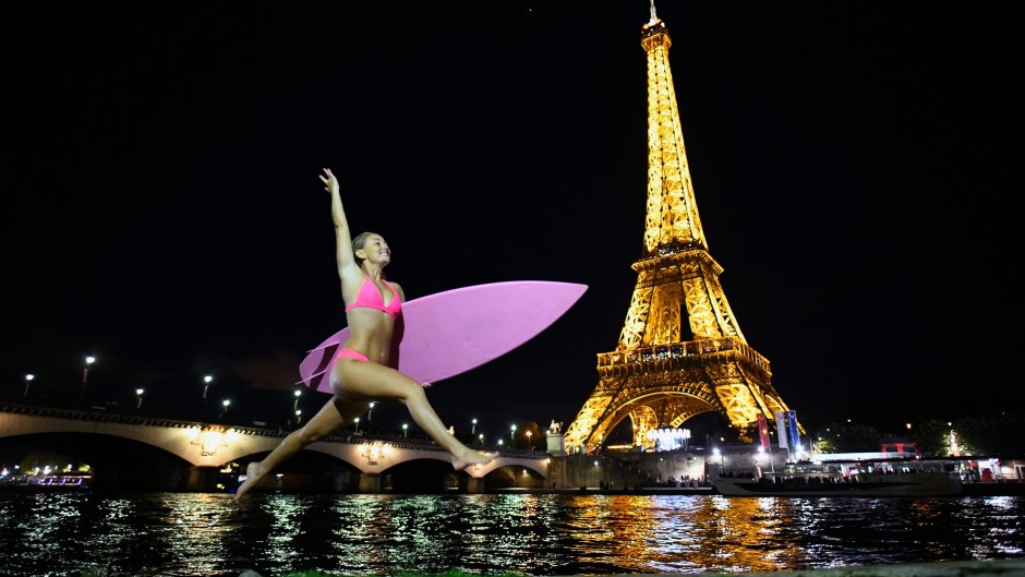 US surfer and adventurer Alison Teal jumps with her surfboard next to the Seine River in front of the Eiffel Tower in Paris.