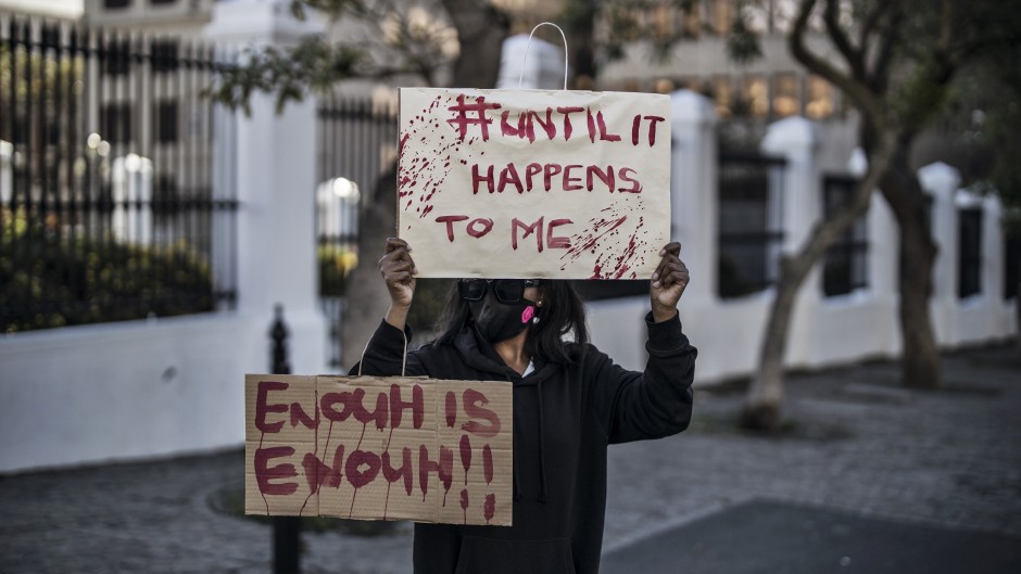 A woman holds placards as she demonstrates against gender-based violence outside Parliament.