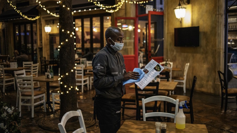 A waiter sanitises the menu of a restaurant at the Montecasino complex.