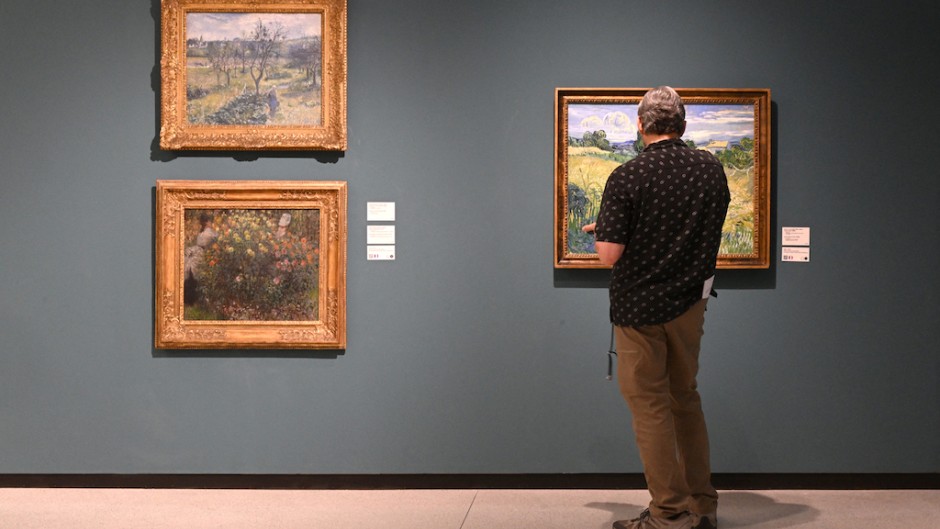 A visitor looks at a painting by Vincent van Gogh (R) next to paintings by Claude Monet and Camille Pissarro. AFP/Michal Cizek