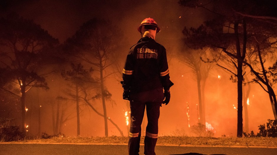 A firefighter stands during operations to put out a forest fire on Signal Hill, a popular lookout point and hike for tourists, above the city centre on March 15, 2020, in Cape Town. 