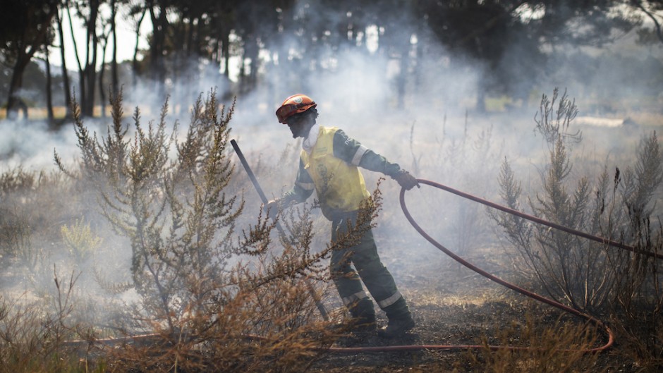 A firefighter doses a smouldering fire to prevent spreading on the outskirts of Scarborough. AFP/Gianluigi Guercia