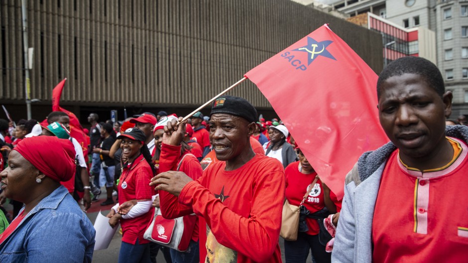 File: A man (C) holding a flag of the South African Communist Party (SACP) in Johannesburg, South Africa. 