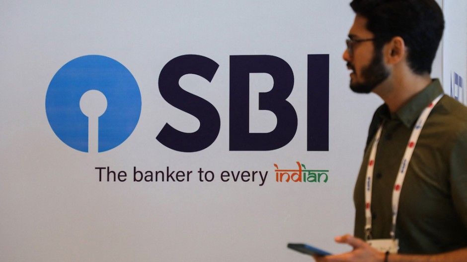 A man walks past a State Bank of India (SBI) logo. NurPhoto via AFP/Niharika Kulkarni