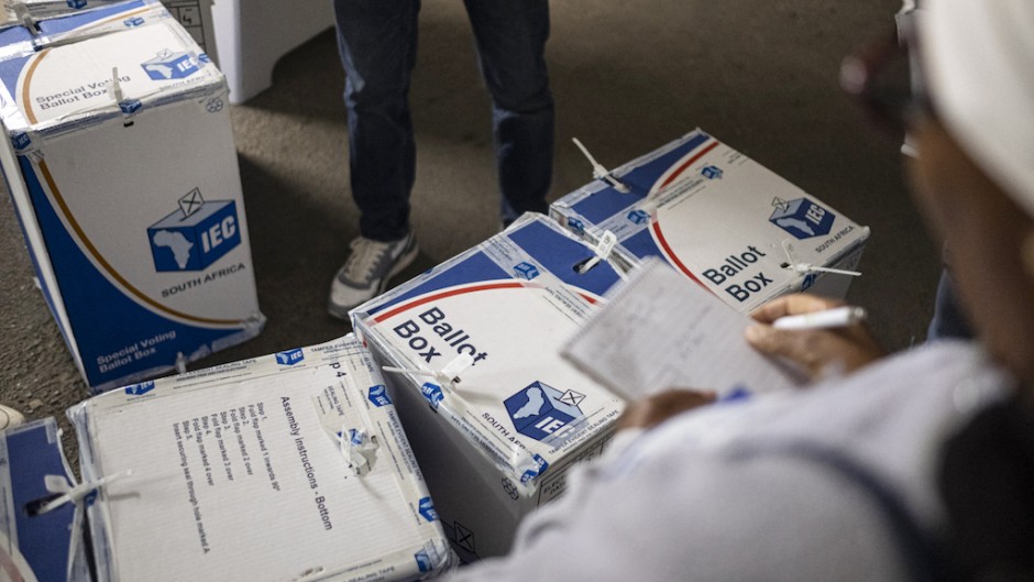 An election observer writes down notes as an IEC official tapes ballot boxes shut. AFP/Emmanuel Croset