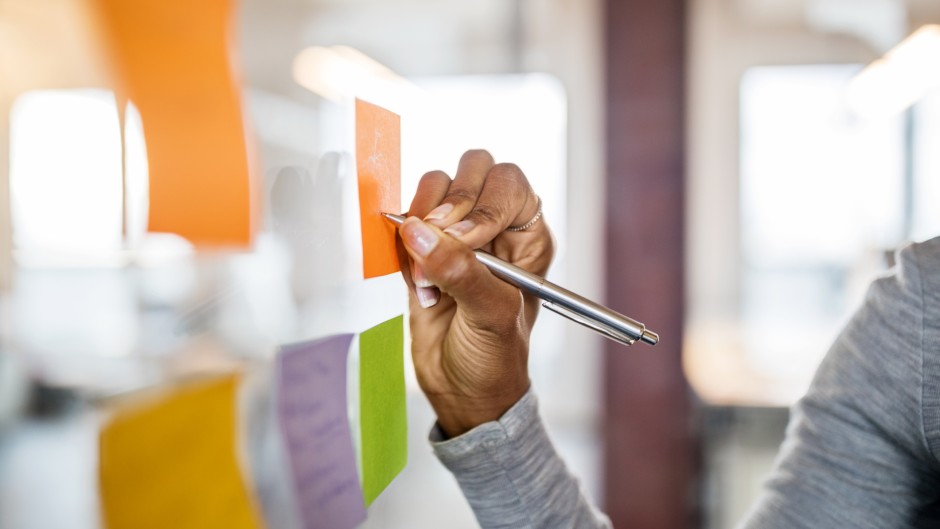 File: A woman/student writing on a sticky note. Getty Images/Luis Alvarez