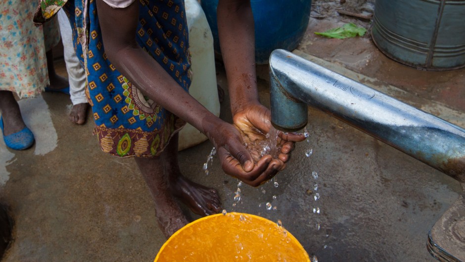 File: A woman washes her hands and drinks water from a borehole. Getty Images/Guido Dingemans/De Eindredactie