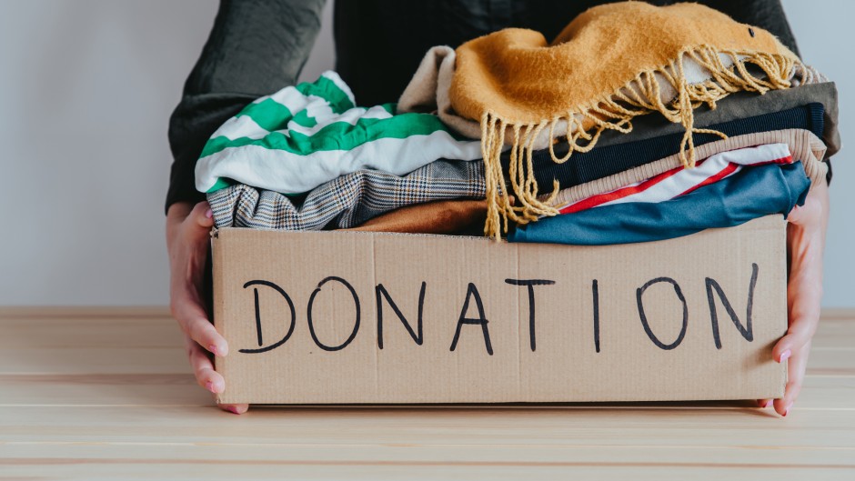 File: A woman holding a donation box filled with clothes. GettyImages/Damian Lugowski