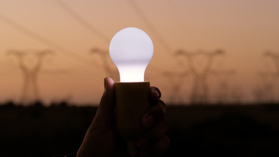 File: A person holds a lightbulb with electricity cables for supply of power. Getty Images/Sean Anthony Eddy